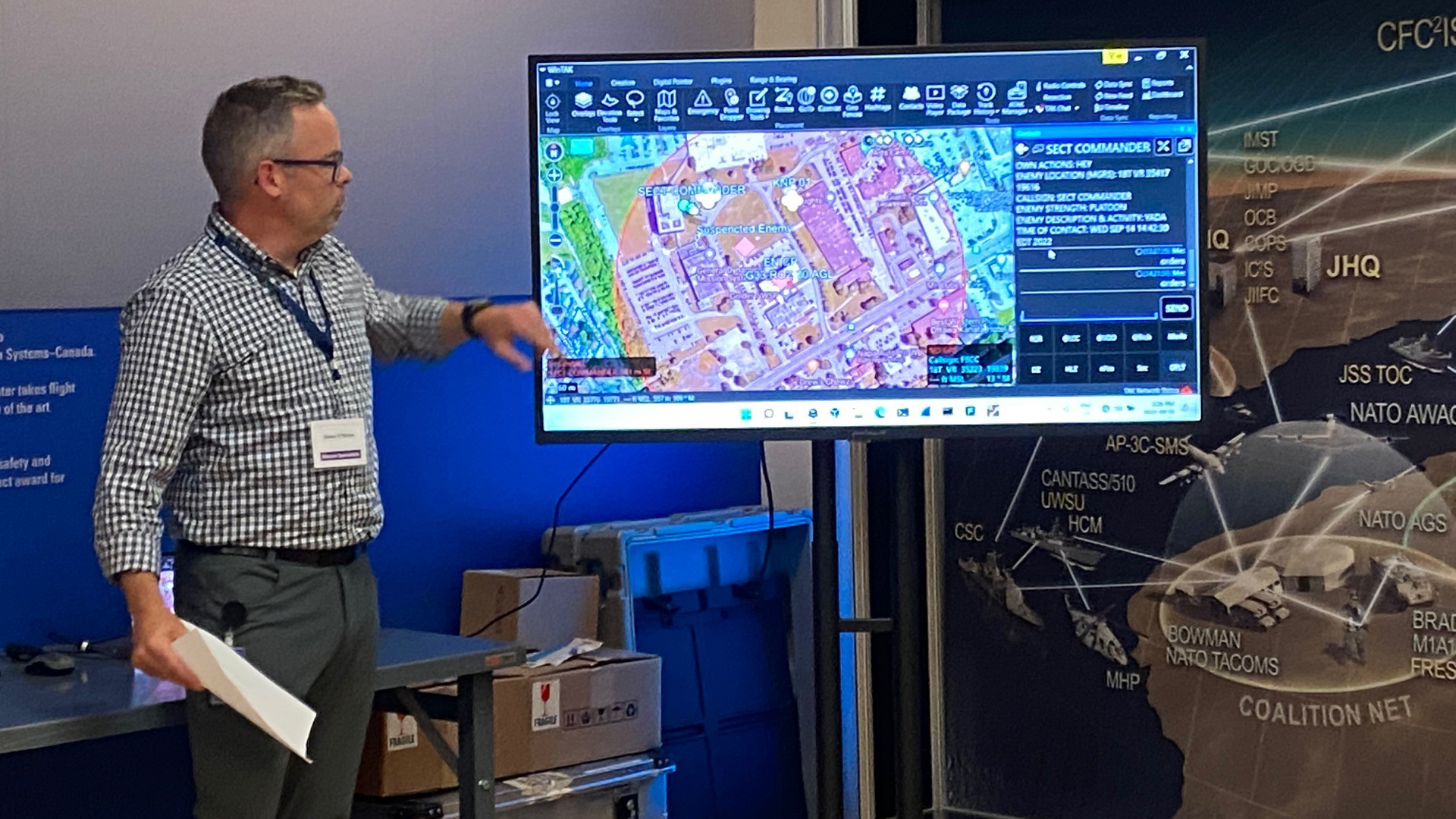 Man in front of screen presenting to audience behind camera