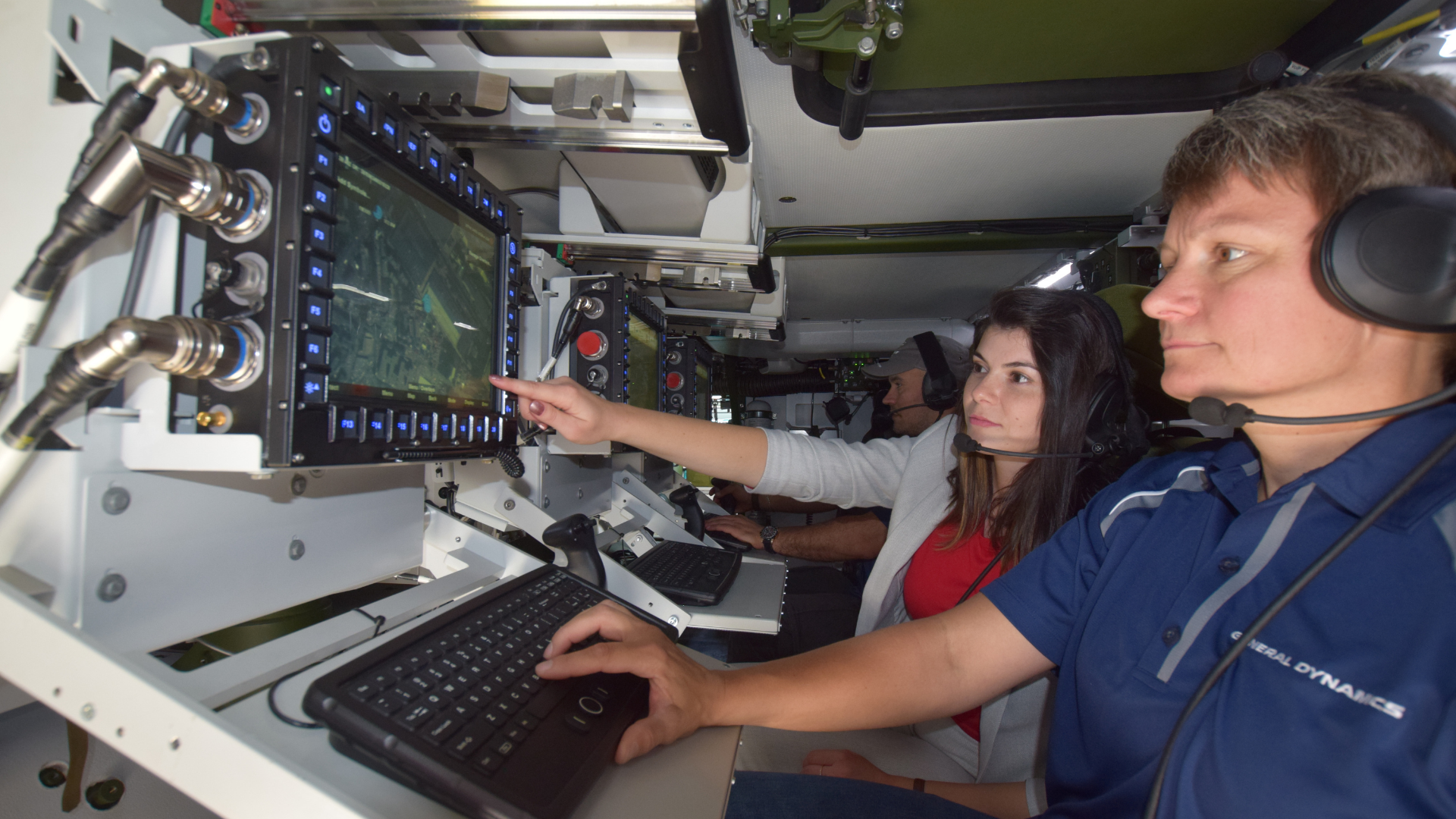 Person pointing at display in military vehicle