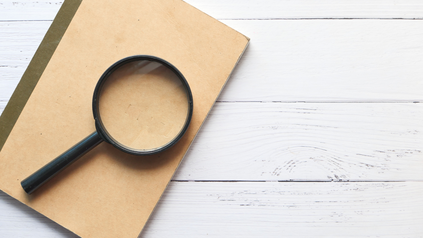 Photo of a magnifying glass placed upon a notebook.