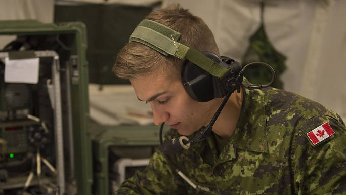 Soldier wearing headset hooked up to radio in tent