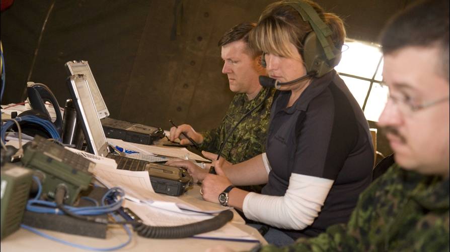 Two men and one woman using military communications equipment